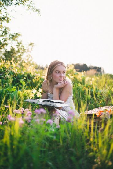 Model reading a book in a field at sunset