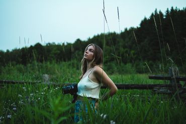 person standing in long grass with camera