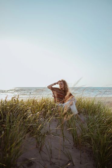 model sitting in long grass on at Sauble Beach during sunset