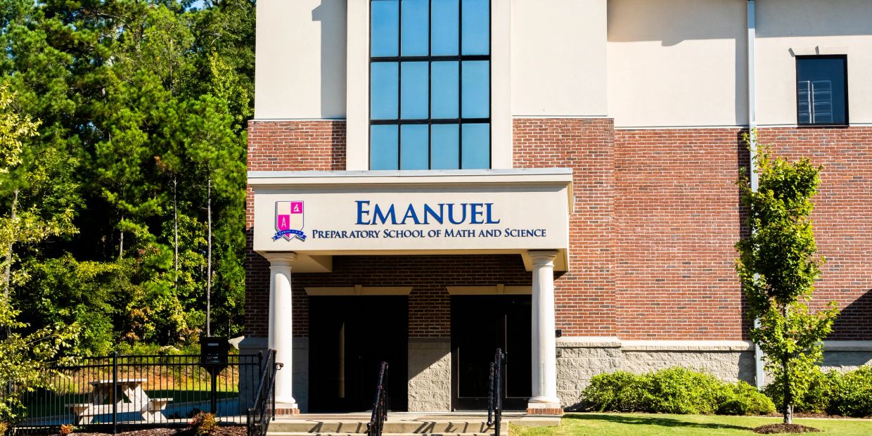 Entrance of Emanuel Preparatory School of Math and Science with brick facade and greenery.