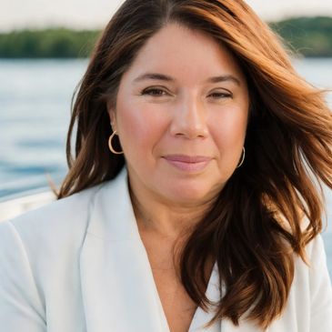 A woman with long brown hair wearing a white blazer outdoors.