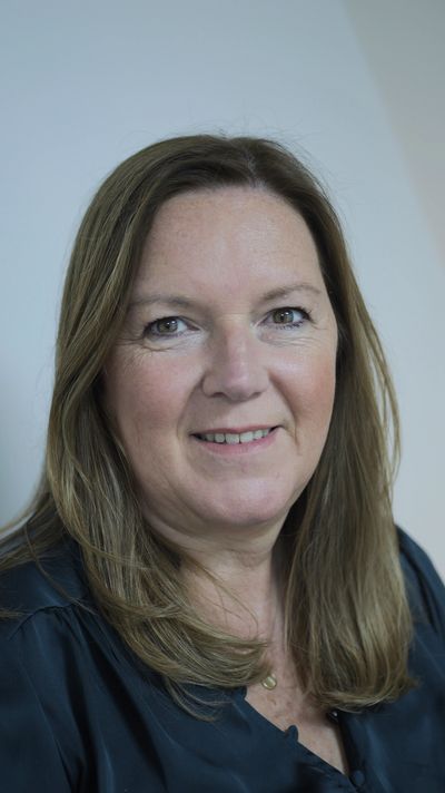 Smiling middle-aged woman with light brown hair and a dark blouse.