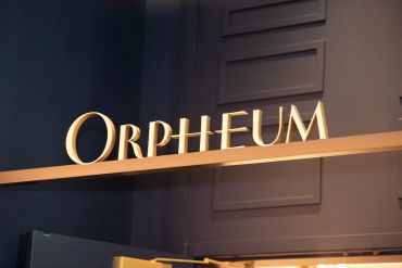 Golden letters spelling 'ORPHEUM' on a shelf against a dark wall.