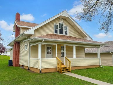 A yellow house with a front porch and a small wooden staircase.