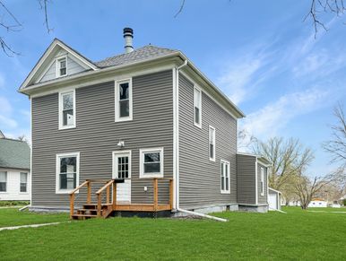 Gray two-story house with white trim and small wooden porch steps.