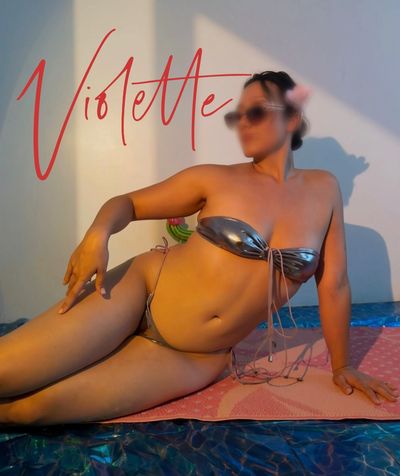 Femme en bikini argenté posant sur un tapis rose.