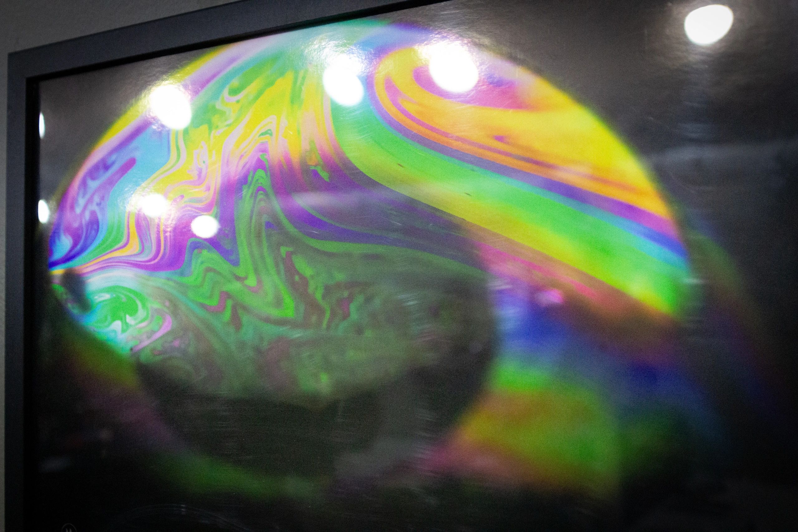 Colorful swirl pattern reflecting light on a dark surface.