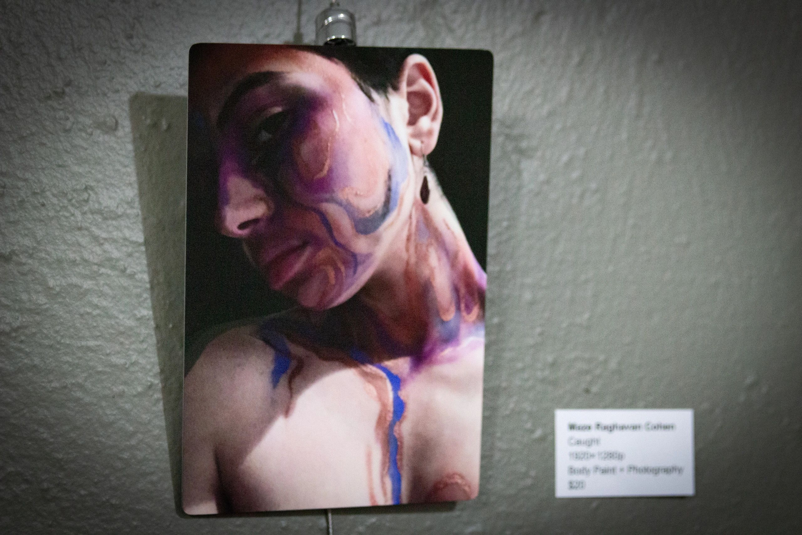 Portrait of a person with colorful body paint on face and chest.