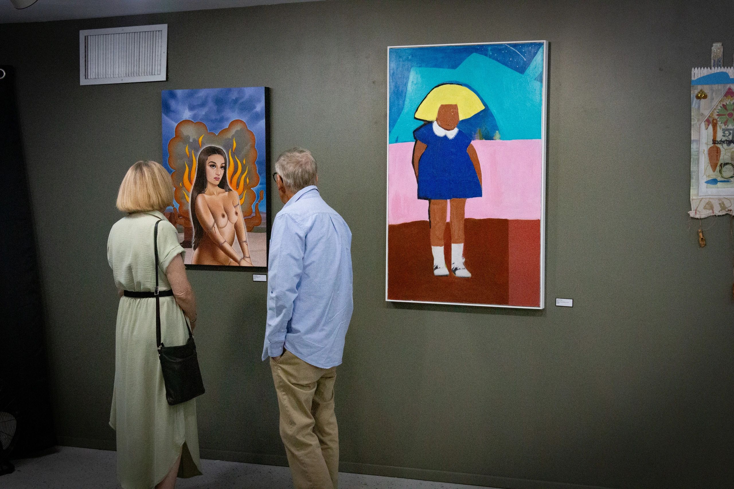 Two people observing bold art pieces in a gallery.