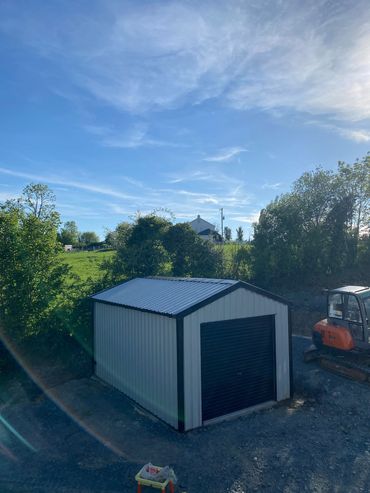 A small metal shed with a black door under a clear blue sky.
