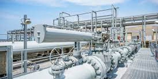 Industrial facility with large pipelines and valves under a clear sky.
