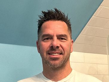 Smiling man with spiked hair in a bathroom setting.