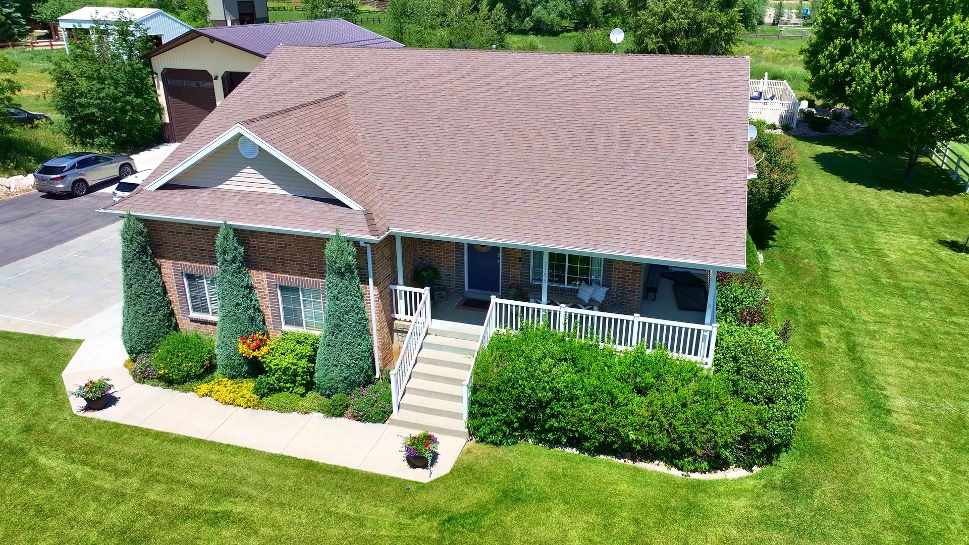 real estate photography of the front of a brick house with pine trees and a blue door