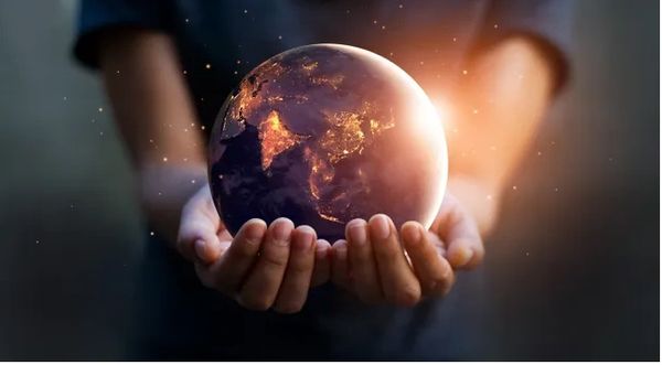 Hands of a child holding up a realistic model of Earth with glowing lights on different countries