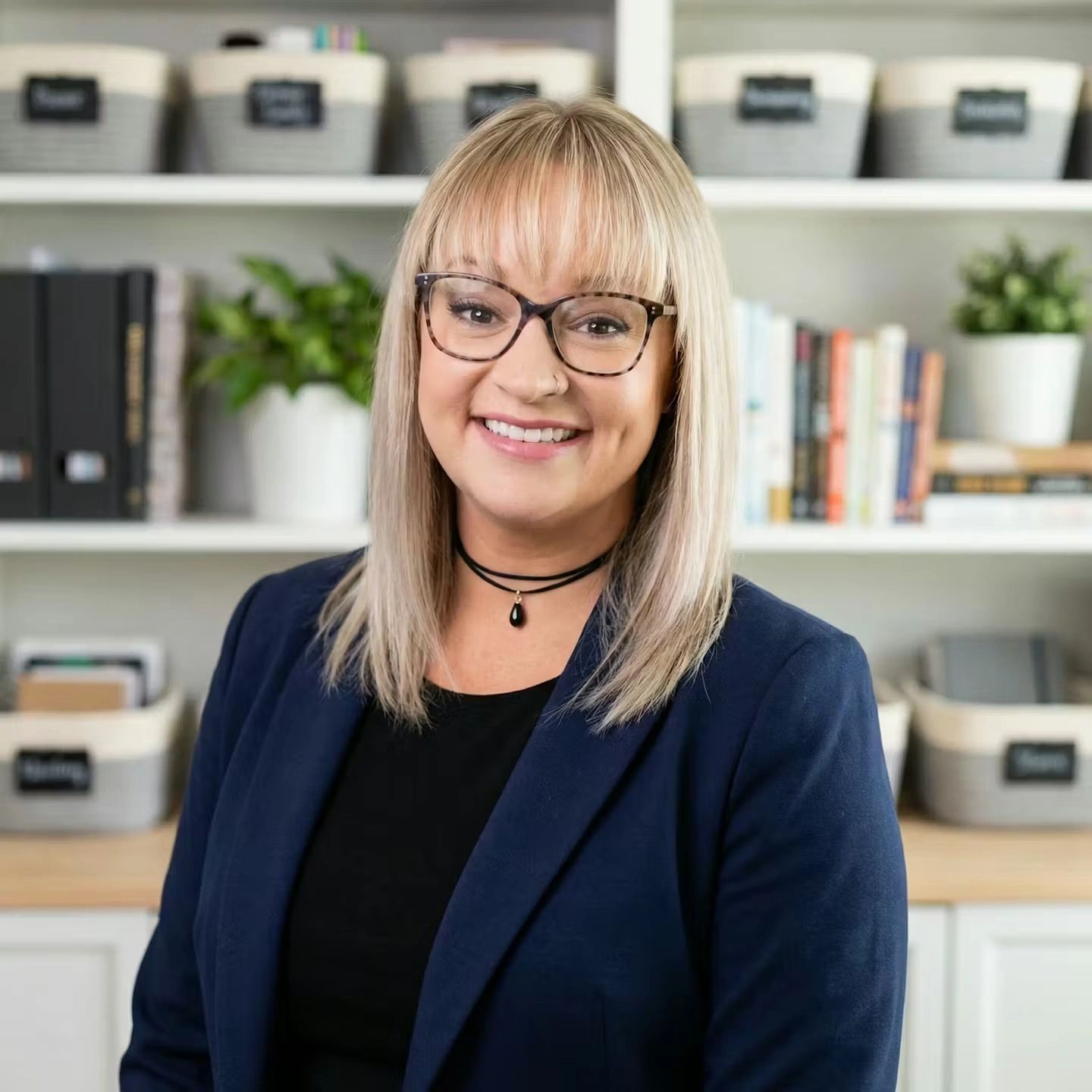 Smiling woman with glasses in a professional setting.