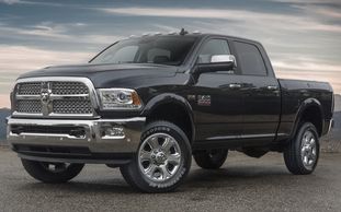 Black Dodge Ram pickup truck parked on a gravel surface.