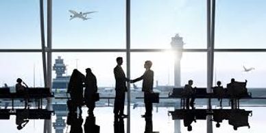 Two people shaking hands in an airport terminal with planes outside.