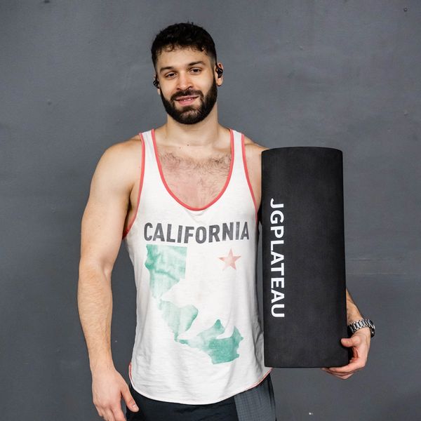 Man in a California tank top holding a JGPlateau foam roller.