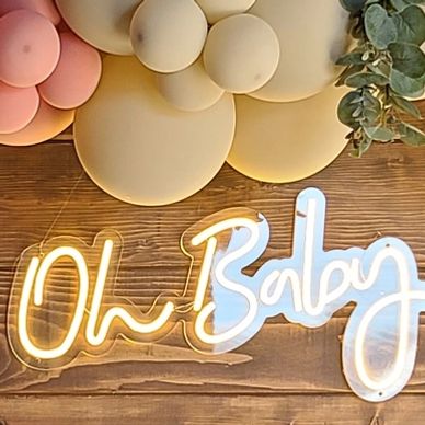 Couple celebrating a baby shower with balloons and a wooden backdrop. Photobooth rental, balloon decor, and other party rentals in Tehachapi.