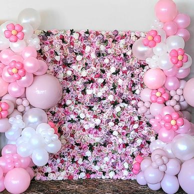 Pink and white floral balloon arch with a flower wall backdrop.