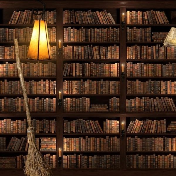 Magical library with floating book, broom, and glowing feather quill.