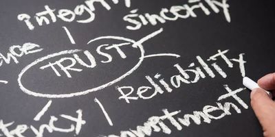 Trust surrounded by key values like integrity and reliability on a chalkboard.
