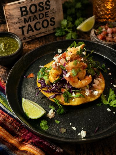 Delicious shrimp taco with fresh toppings on a black plate.