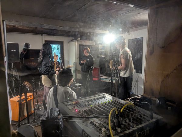 Band rehearsing in a dimly lit room with music equipment.