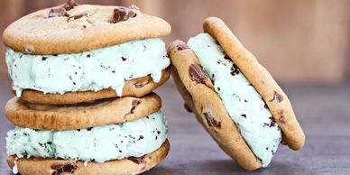 Three chocolate chip cookie ice cream sandwiches with mint chocolate chip filling.