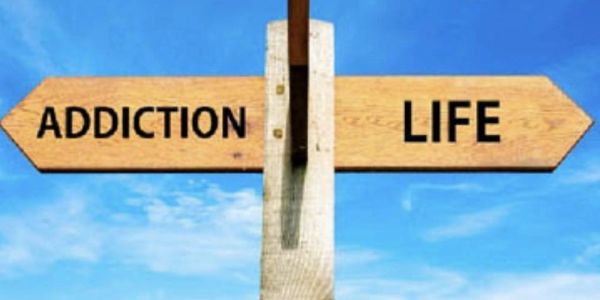 Wooden signpost pointing to 'Addiction' one way and 'Life' the other.