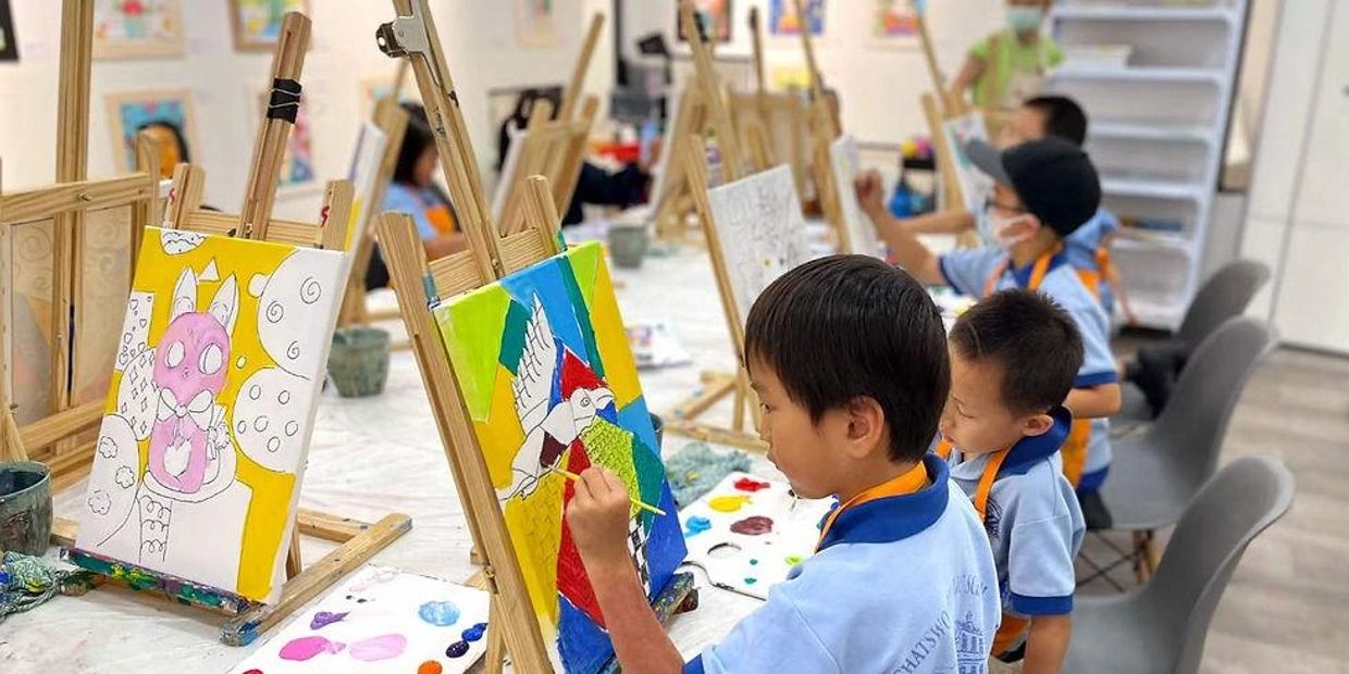 Children painting on easels in a classroom.