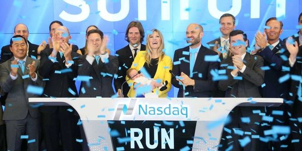 Group of about 12 Sunrun affiliates clapping and celebrating at the stock exchange going public 