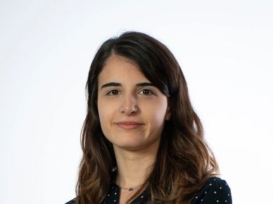 Professional woman with long brown hair and a neutral expression.