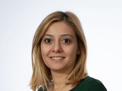 Portrait of a smiling woman with shoulder-length blonde hair in a green top.