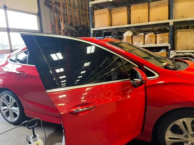 A bright red car with darkened windows. The car has tints on the windows, 