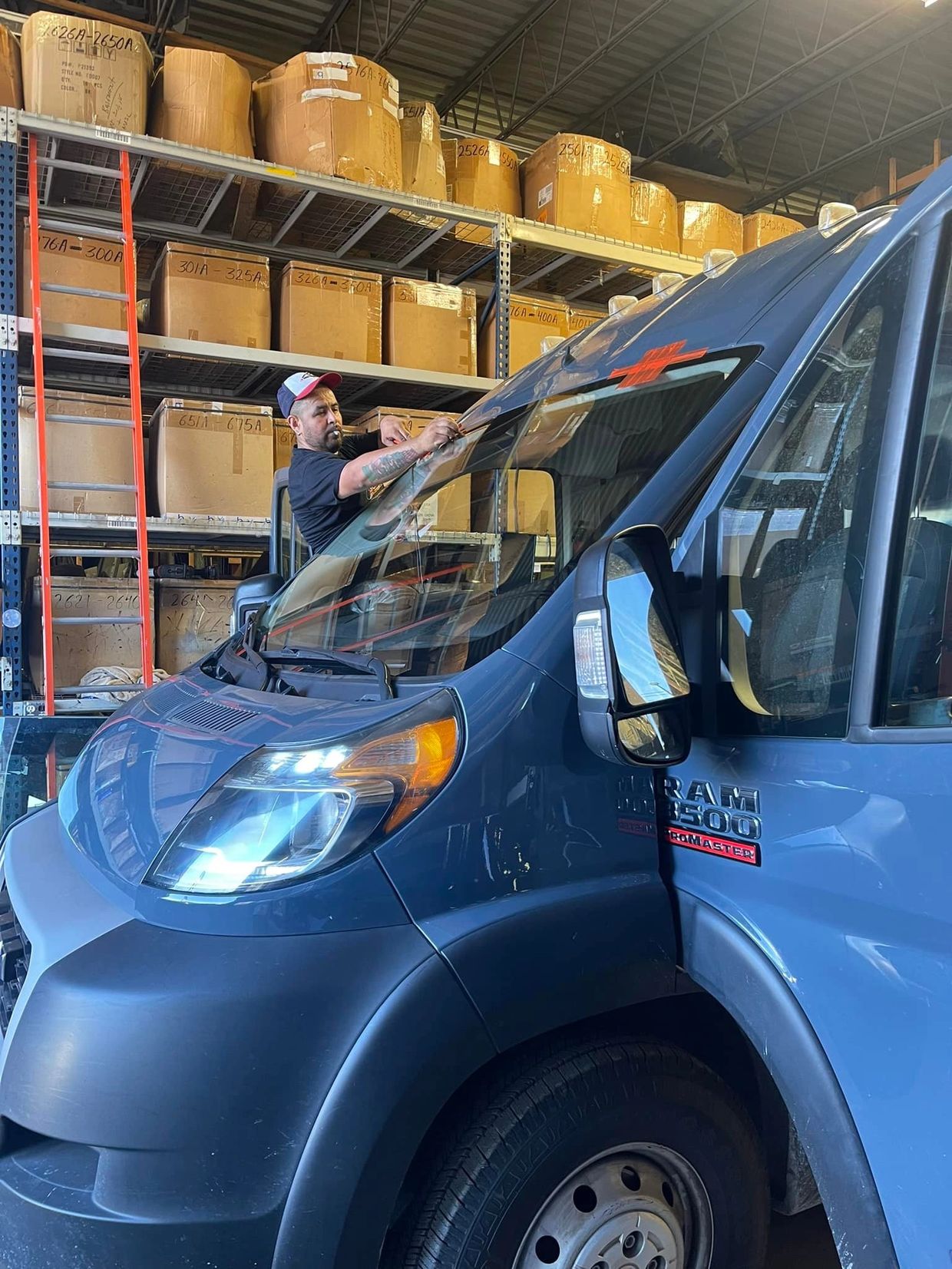 persona remplazando un panoramico o parabrisas en una camioneta azul