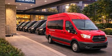 A red hotel shuttle van parked outside a hotel entrance.