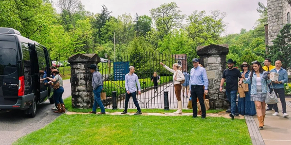 A group of people entering a gated park area near a van.