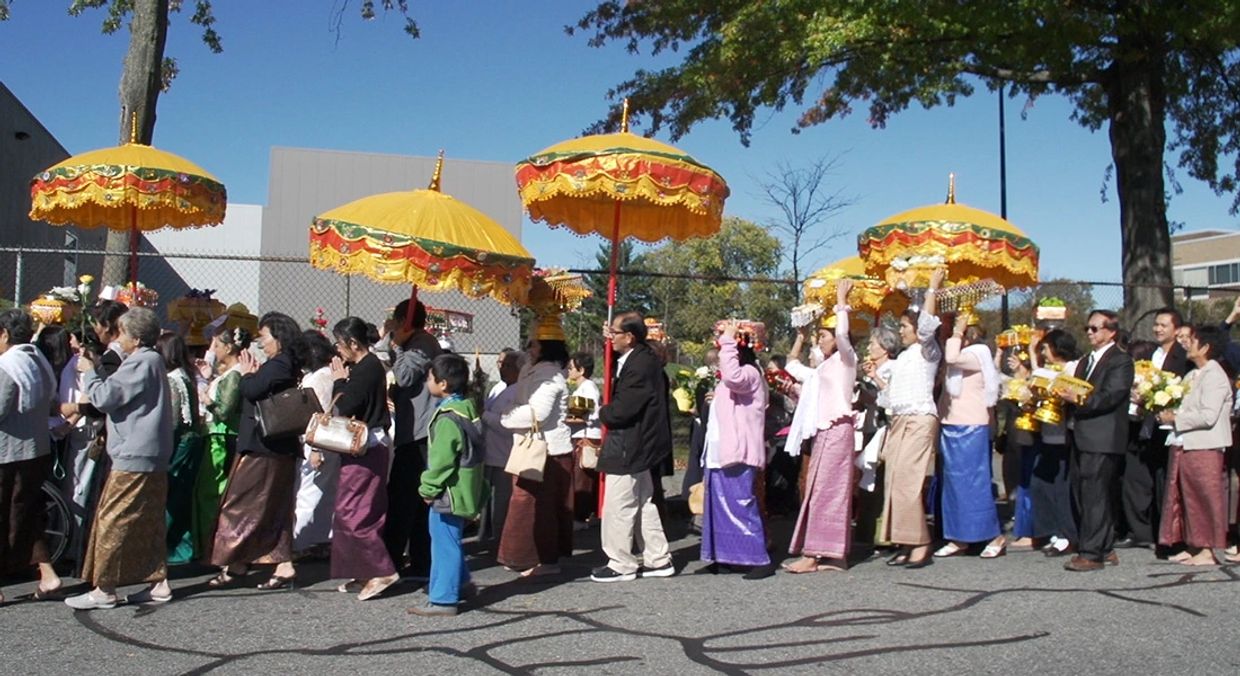 A procession of people holding yellow decorative umbrellas