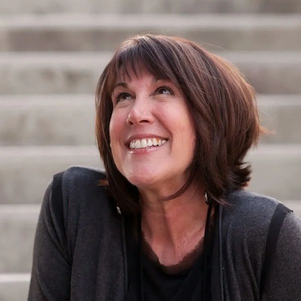 A woman with short brown hair smiling and looking upwards.