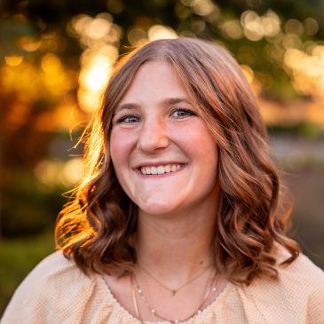 Smiling young woman with curly hair in natural light.