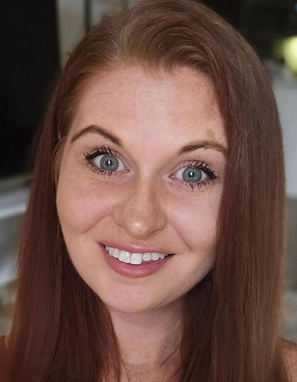 Smiling woman with red hair and blue eyes.