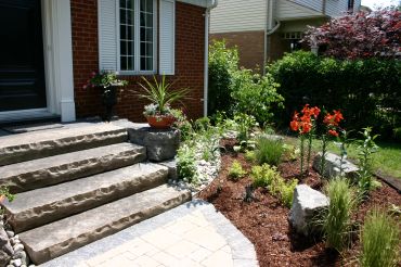 Well-maintained front garden with stone steps and flowers.