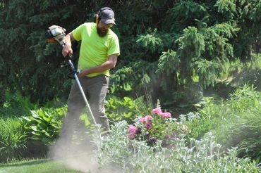 Man using a string trimmer in a garden.