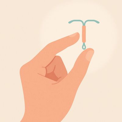Hand holding a small intrauterine device (IUD) for birth control.