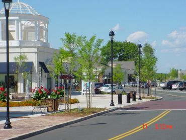 Sunny day at a modern shopping plaza with trees and benches.