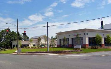 A modern bank building at a street intersection with traffic lights.