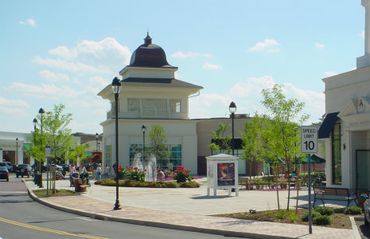 Outdoor shopping center with fountain and benches on a sunny day.