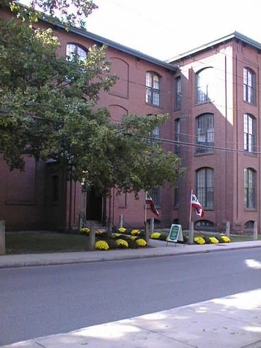 Historic red brick building with large windows and trees outside.