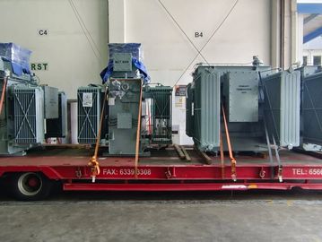 Large electrical transformers secured on a flatbed truck inside a warehouse.